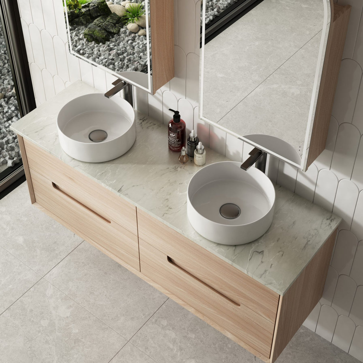 Bathroom vanity with two round sinks, mirrors, and toiletries on a tiled wall.