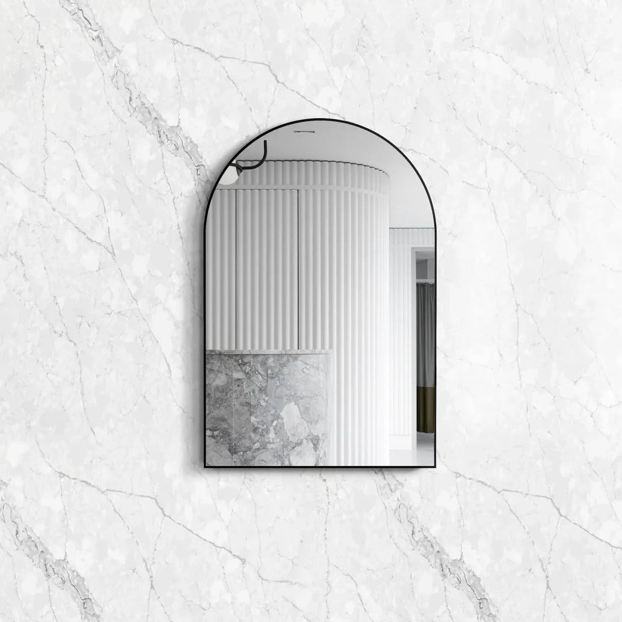 Archie 900x600 Black Metal Framed Mirror with an elegant arched design, reflecting a modern interior against a polished white marble-textured background.