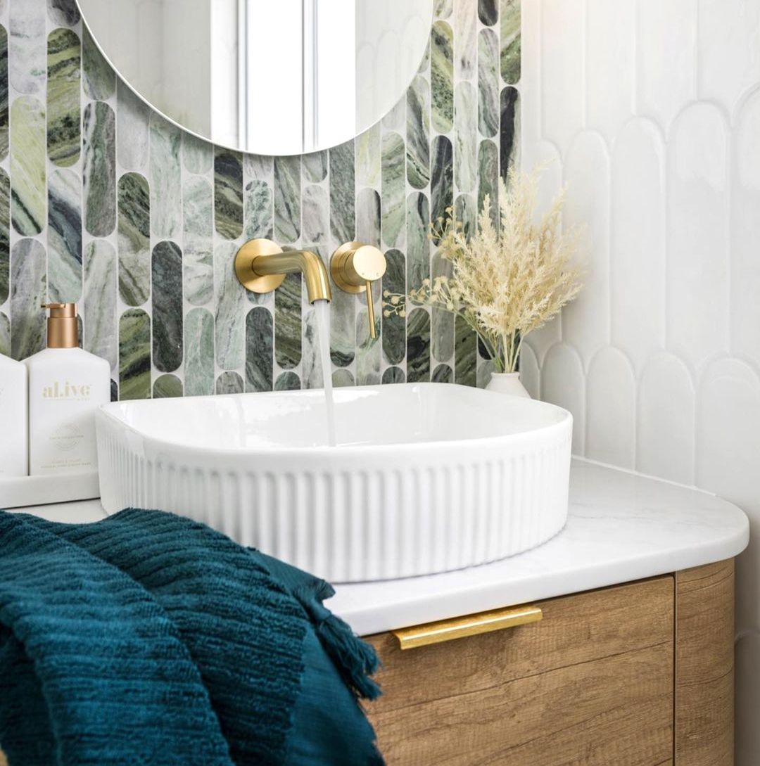 A white sink with gold fixtures in a modern bathroom