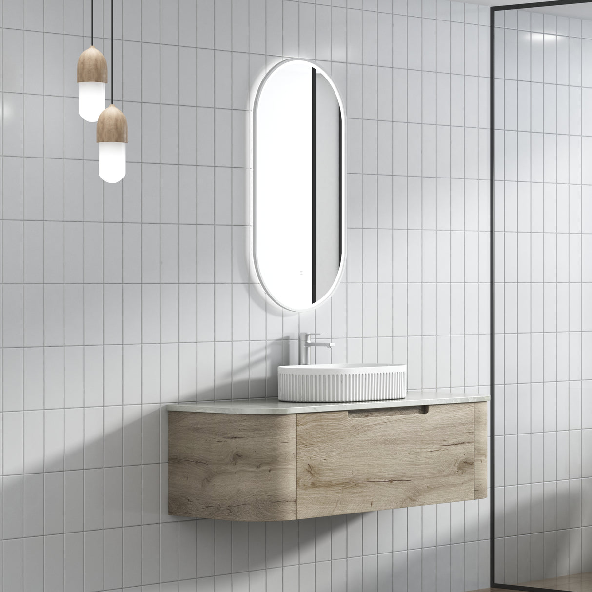 Bathroom with wooden vanity, white sink, and oval mirror against a tiled wall.