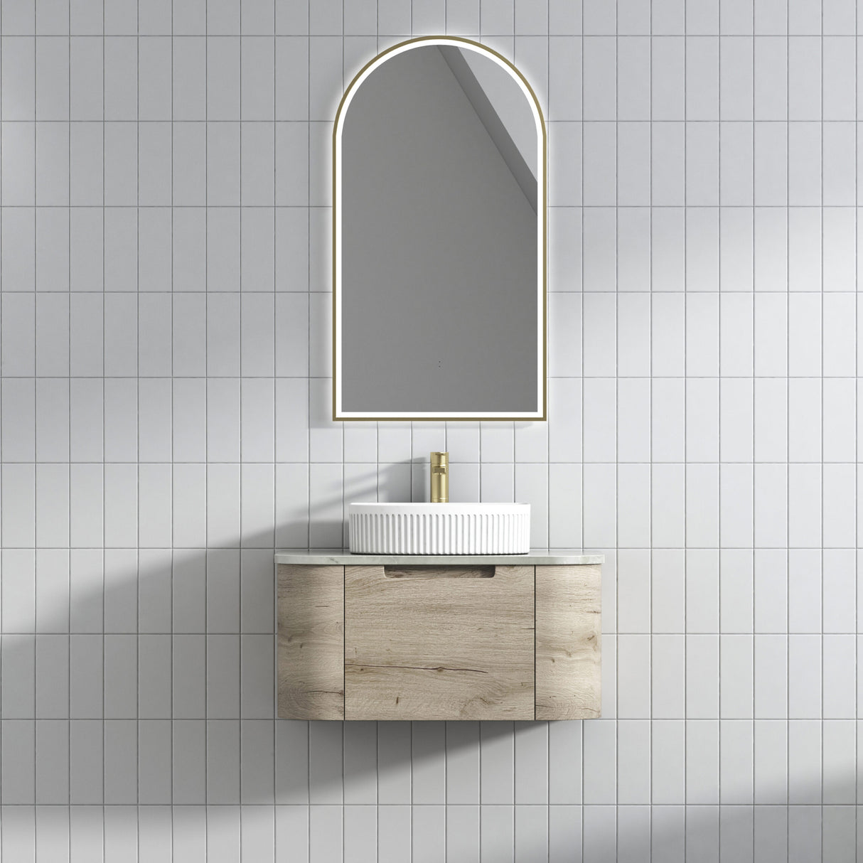 Bathroom vanity with a sink and arch-shaped mirror on a tiled wall.