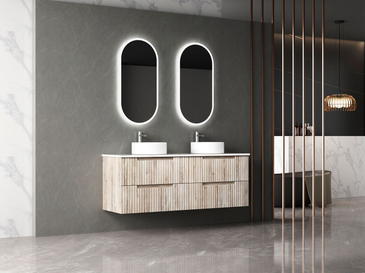 Bathroom vanity with double sink and illuminated mirrors against a gray wall.