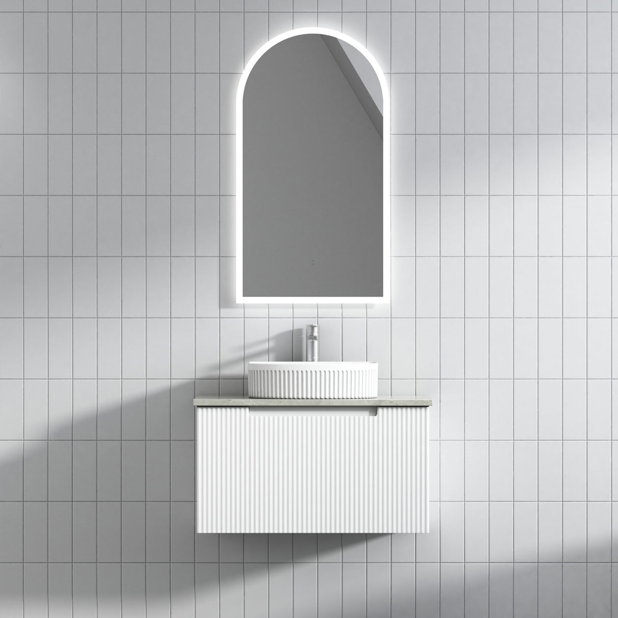 Bathroom vanity with sink and arch-shaped mirror on tiled wall