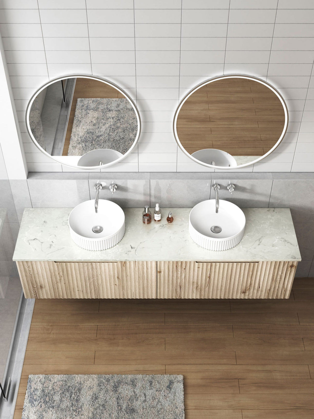 Bathroom vanity with two round mirrors, white sinks, and a marble countertop.