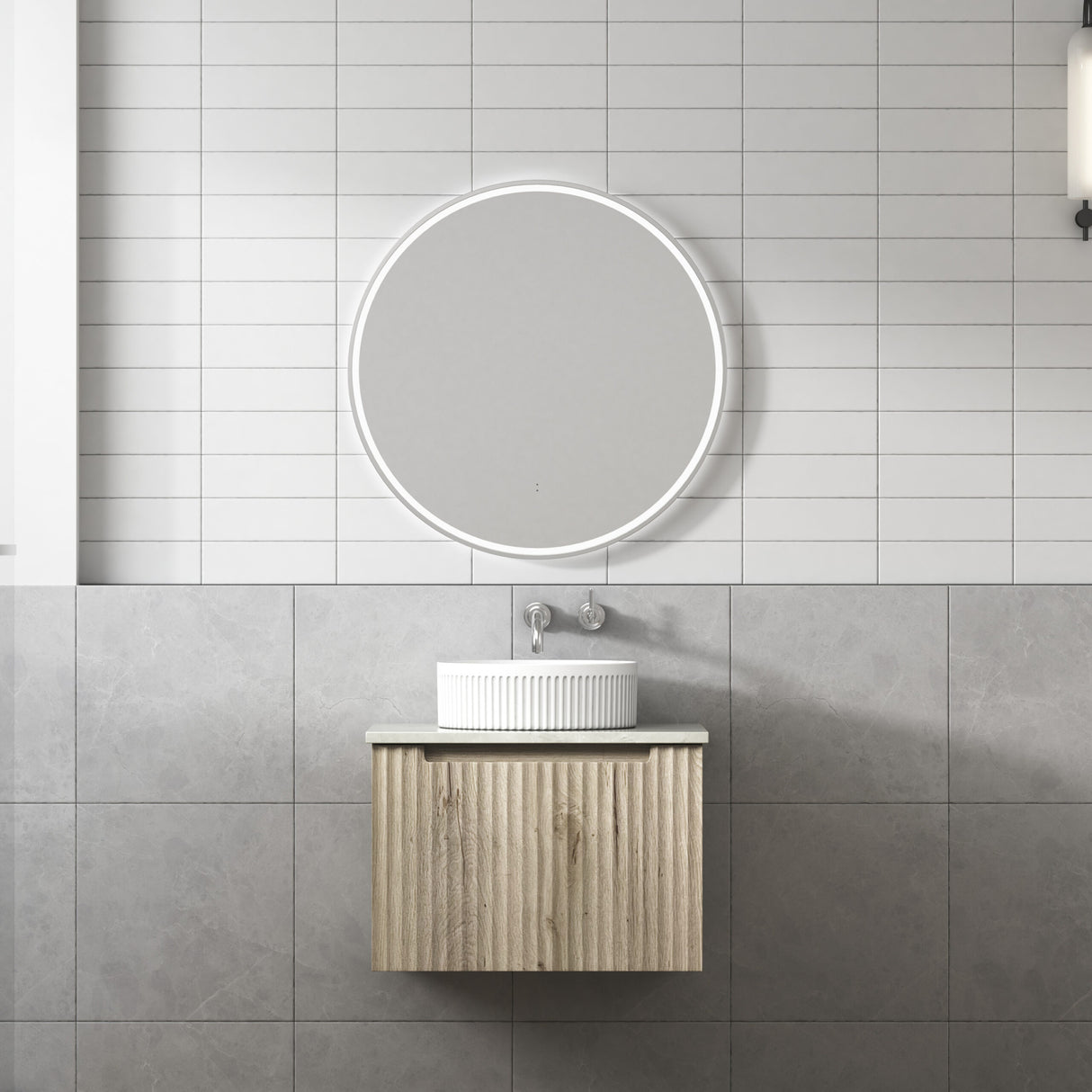 Bathroom with a wooden vanity, round mirror, and tiled walls.