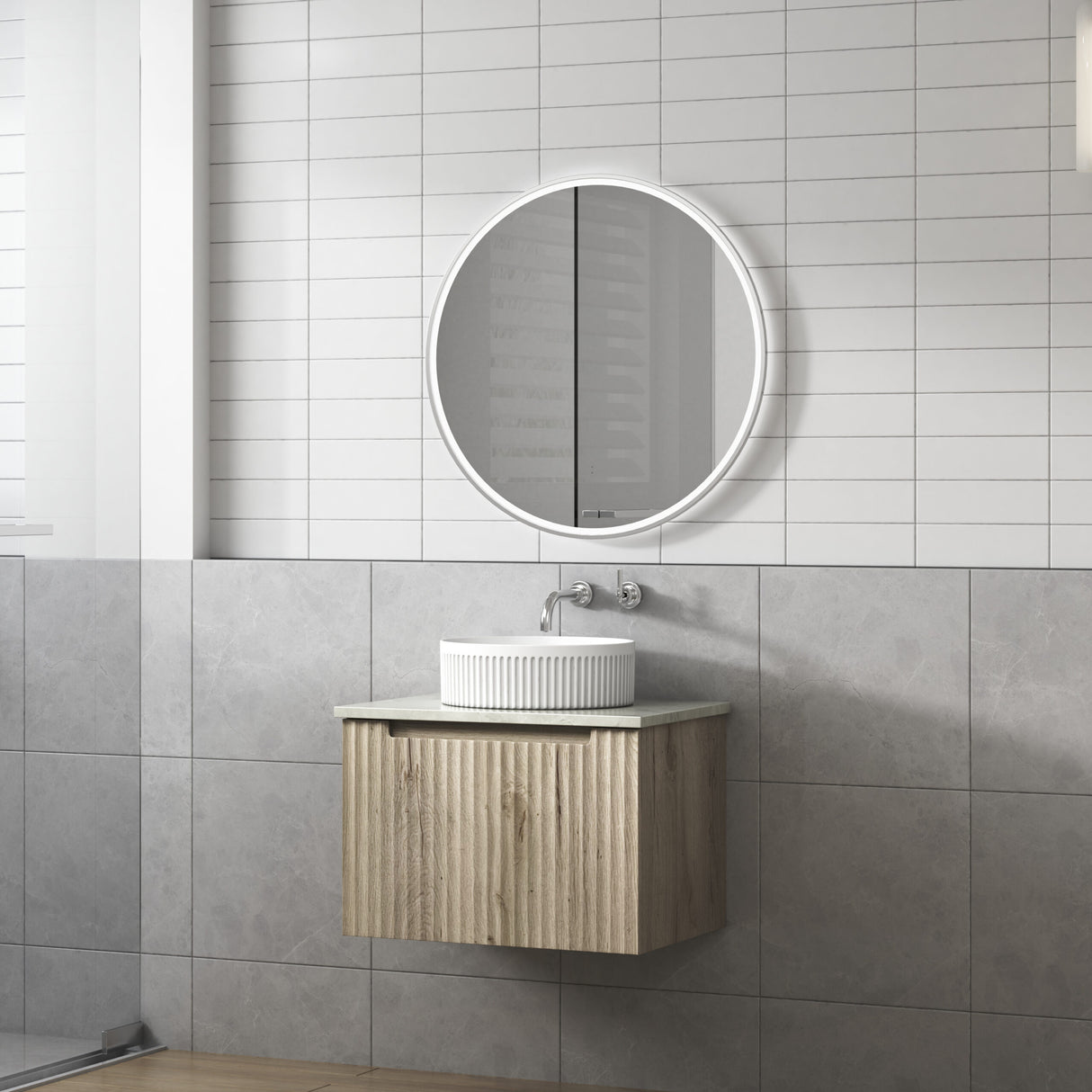 Bathroom with a round mirror above a wooden vanity with a white sink.