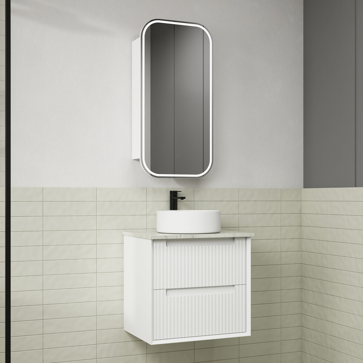 Bathroom vanity with white sink and mirror against a tiled wall.