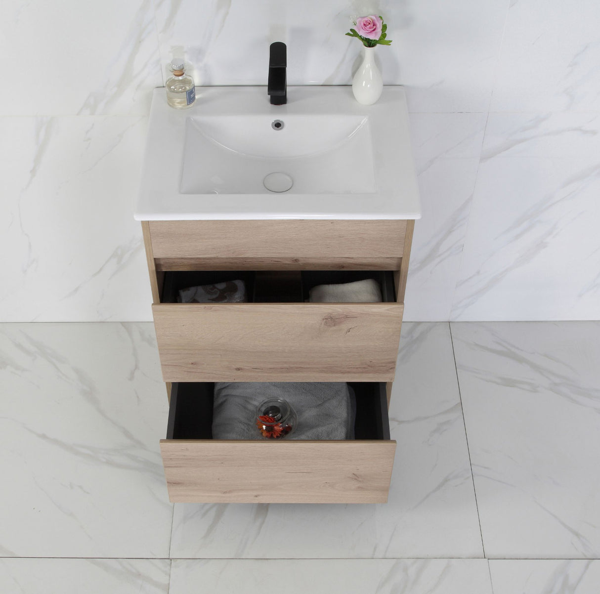 Bathroom vanity with white countertop and wooden drawers on a tiled floor.