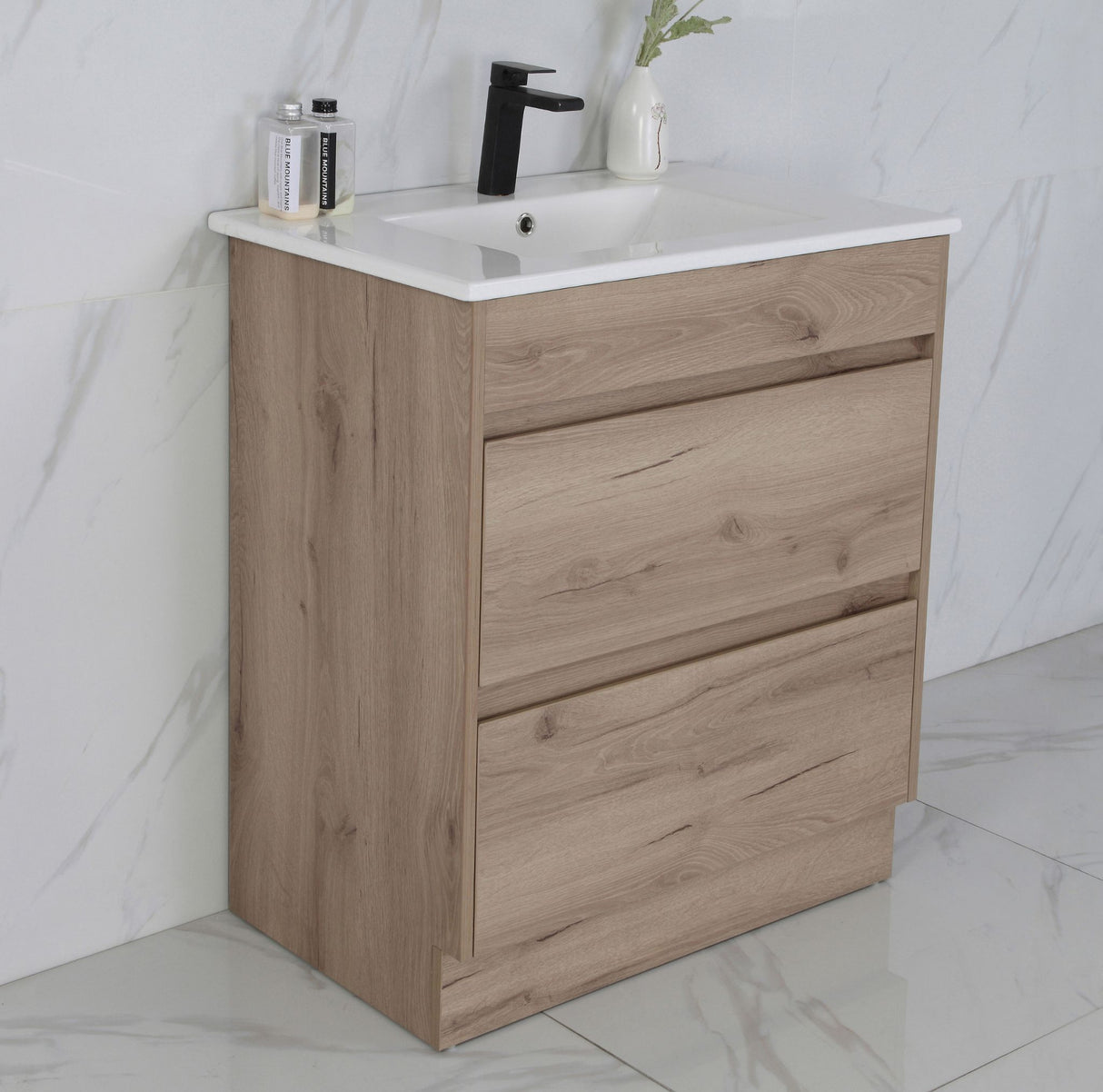 Bathroom vanity with wooden finish and white countertop against a marble wall.