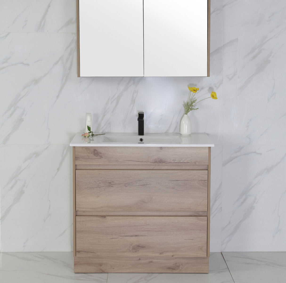 Bathroom vanity with wooden cabinet, white countertop, and mirror against a marble wall.
