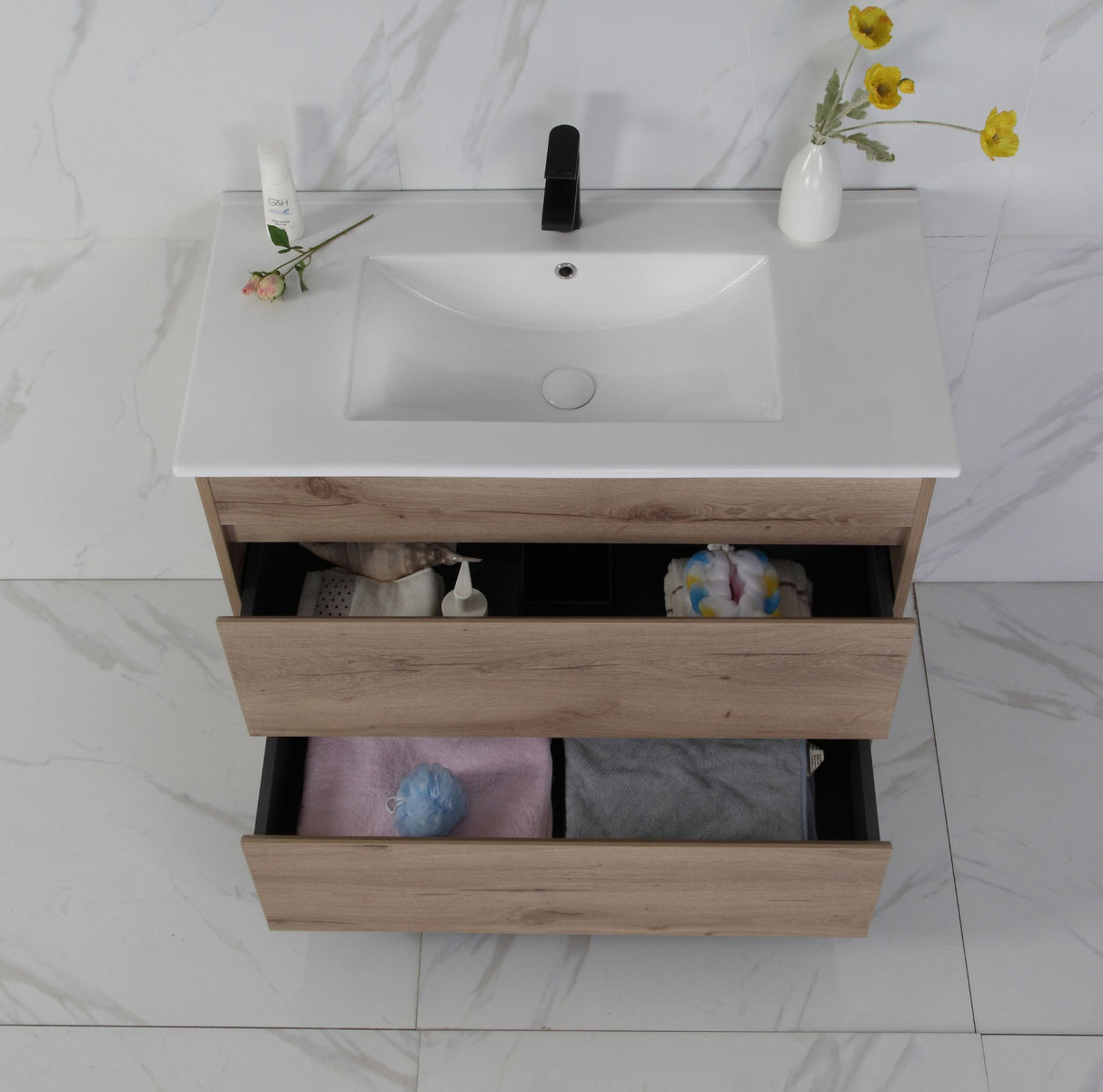 Bathroom vanity with open drawer, sink, and decorative items on a marble floor.