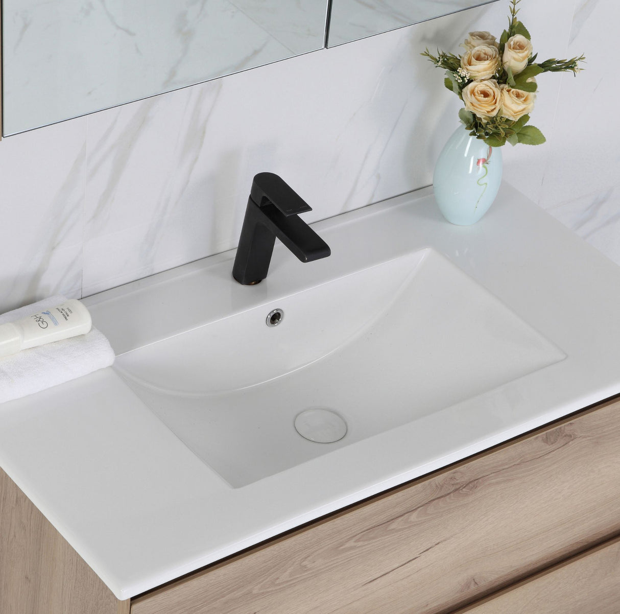 Bathroom vanity with white sink, black faucet, and decorative vase with flowers.