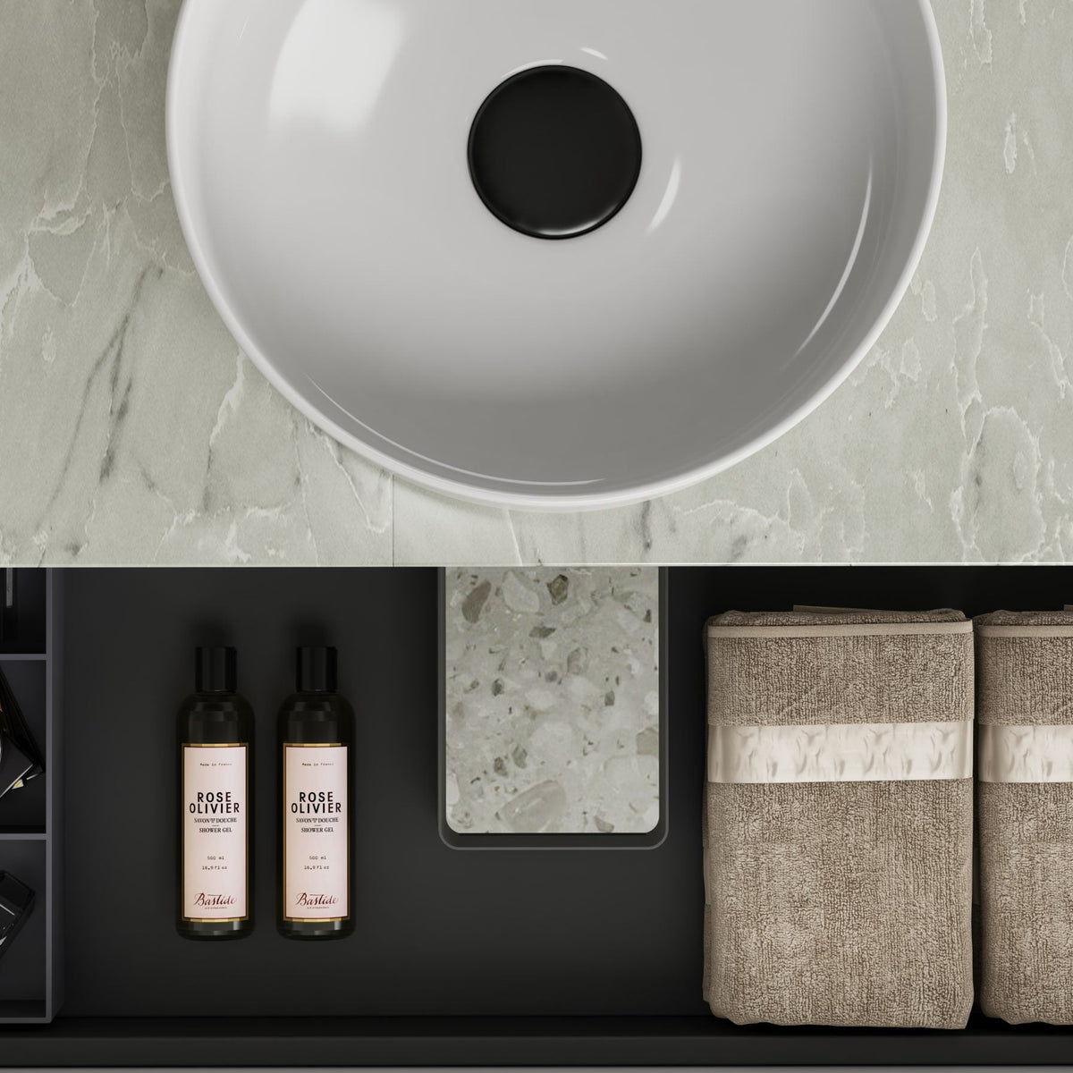 Bathroom counter with a sink, bottles, and towels on a marble countertop.