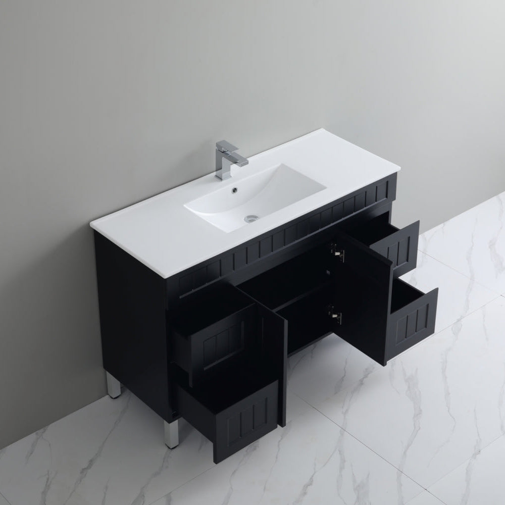 Bathroom vanity with white sink and open drawer against a gray wall.