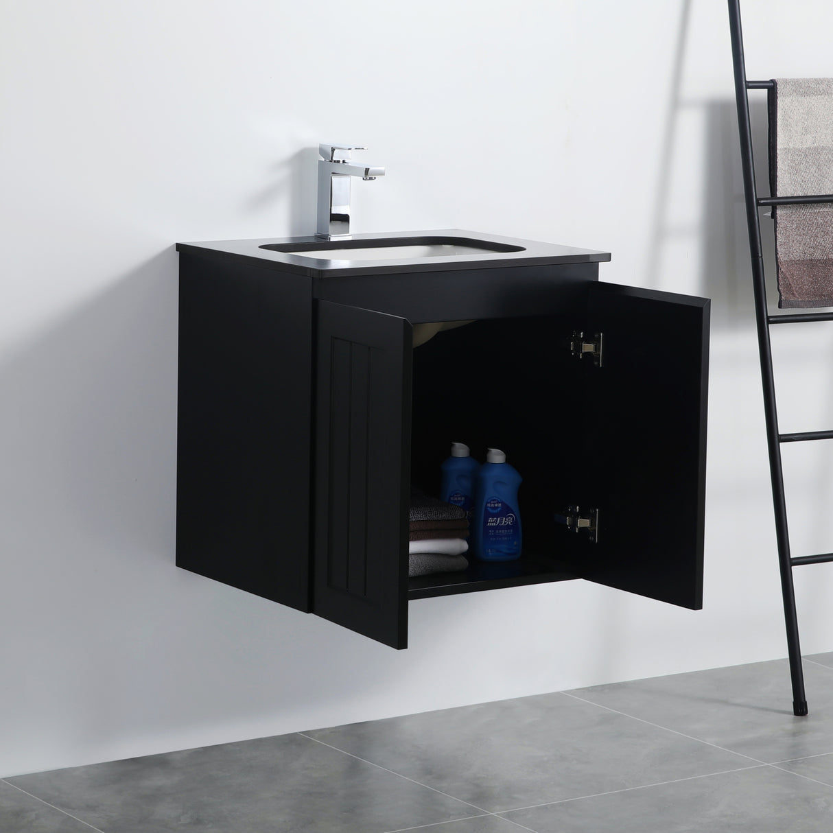 Black bathroom vanity with open cabinet door showing toiletries against a white wall.