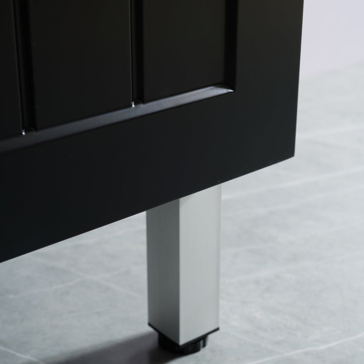 Close-up of a black cabinet leg on a tiled floor