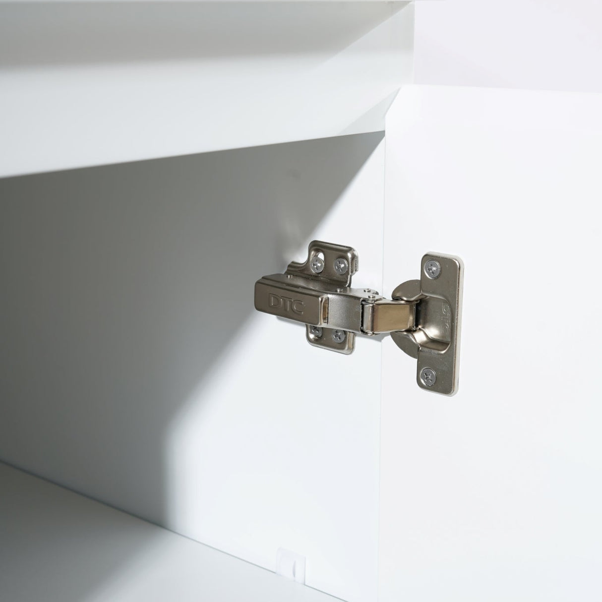 Close-up of a cabinet hinge on a white cabinet