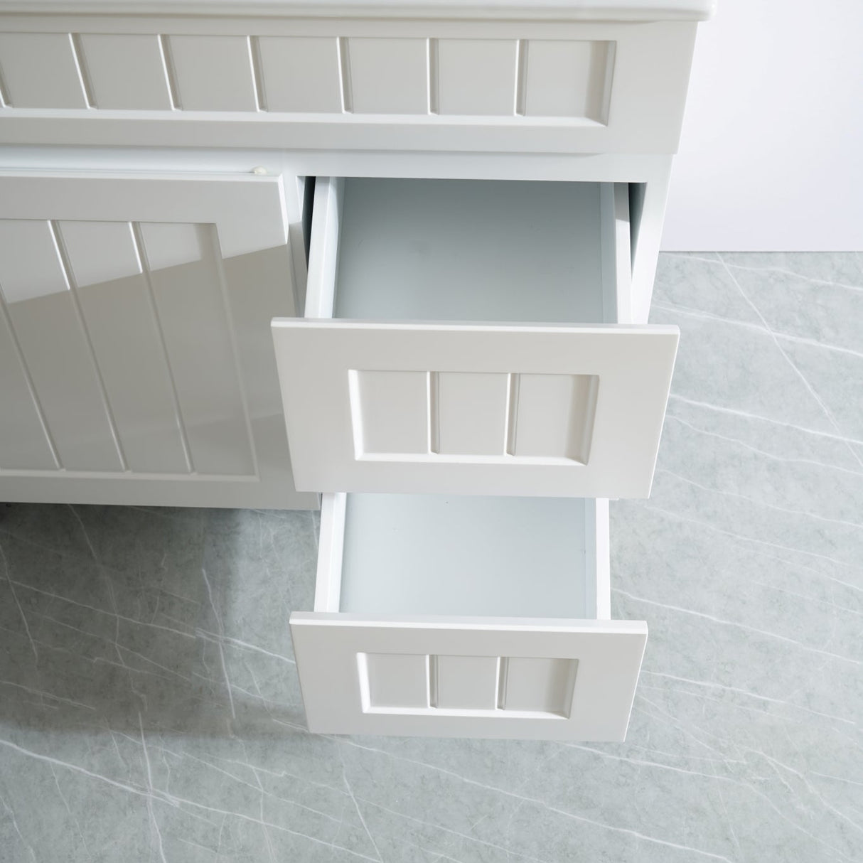 White bathroom vanity with open drawer on a tiled floor