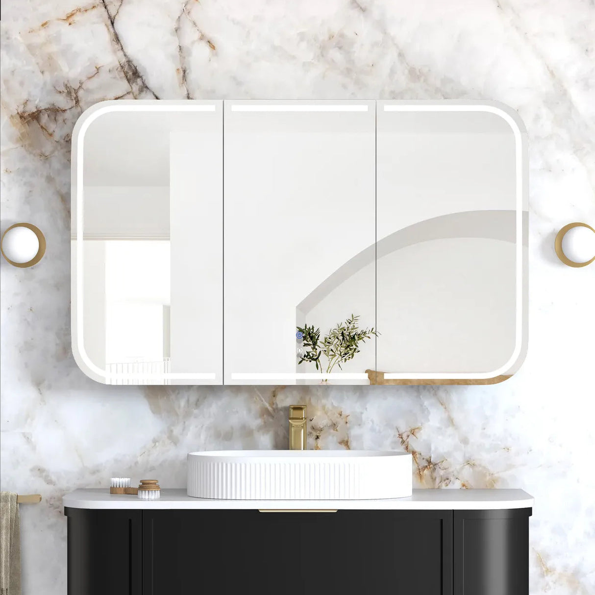 Bathroom vanity with black cabinet, white sink, and gold fixtures against a marble wall.