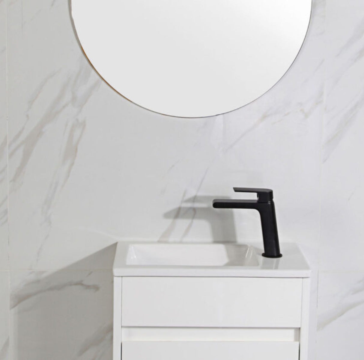 Bathroom vanity with black faucet and round mirror on white marble wall