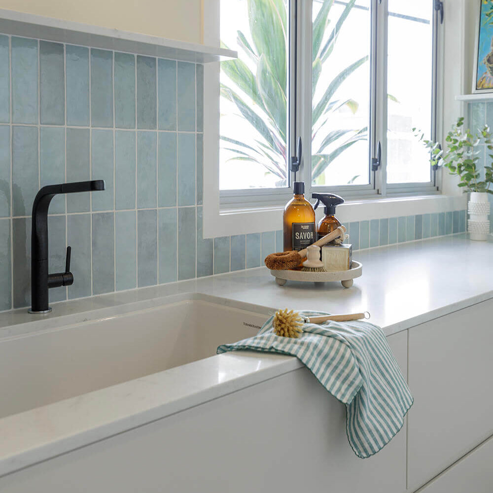 Modern bathroom with bathtub, window, and cleaning supplies.