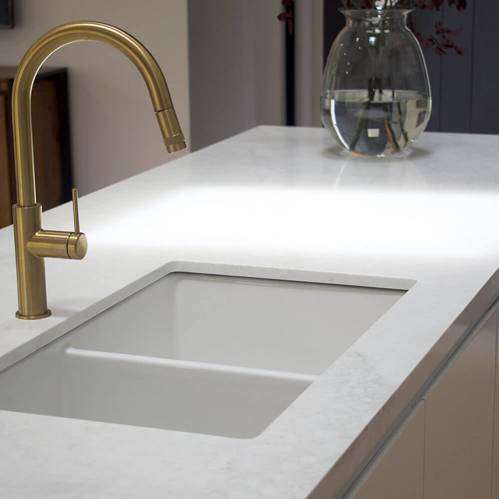 Modern kitchen sink with gold faucet and white countertop