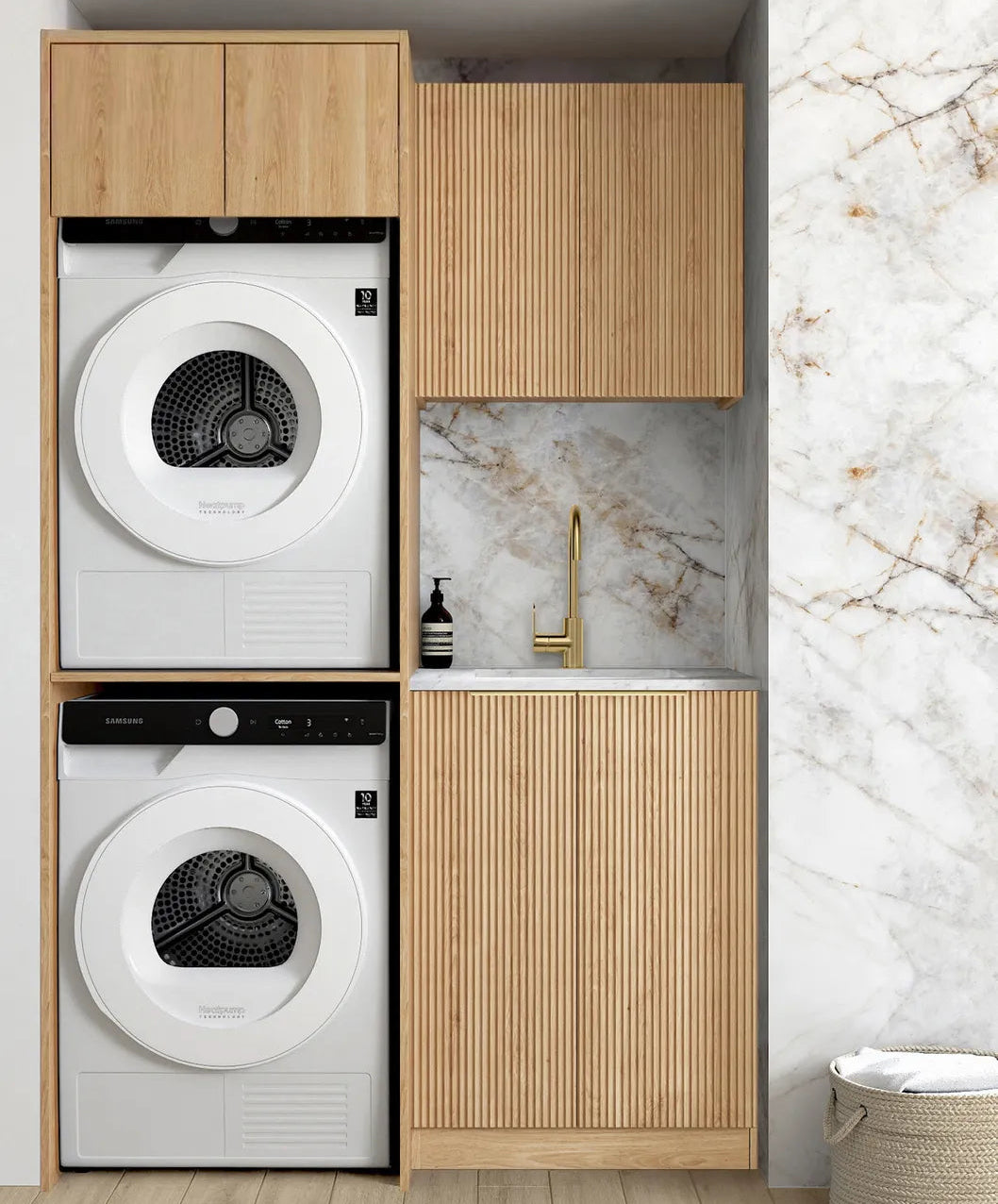 Laundry room with stacked washer and dryer under wooden cabinets against a marble wall.
