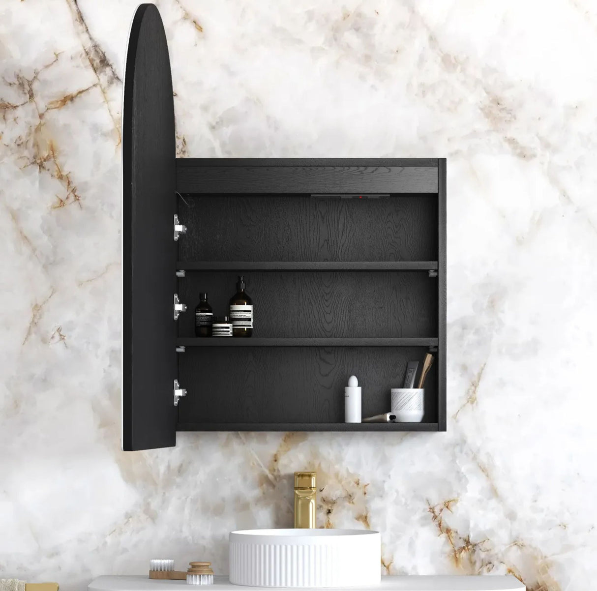 Black wall-mounted cabinet with open door on a marble bathroom wall.