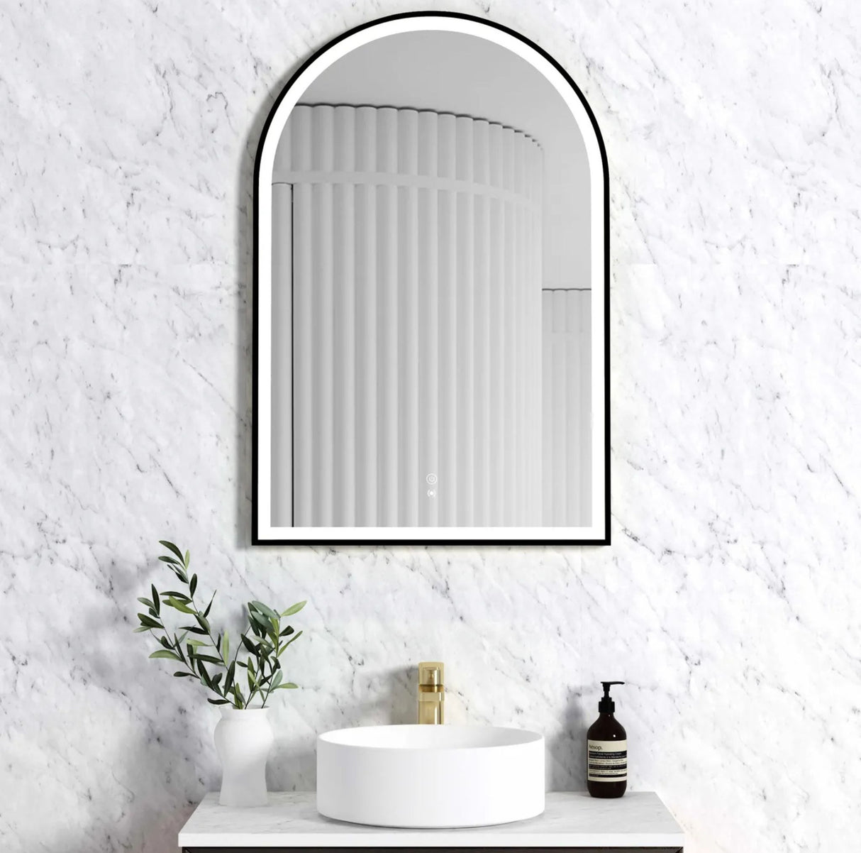 Bathroom with a decorative mirror, sink, and toiletries against a textured white wall.