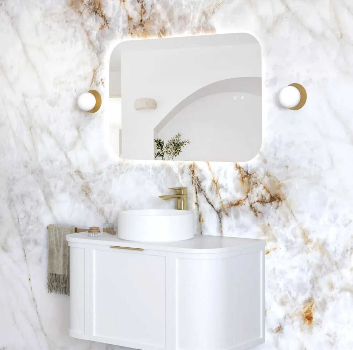 Bathroom vanity with white sink and mirror against a marble wall.