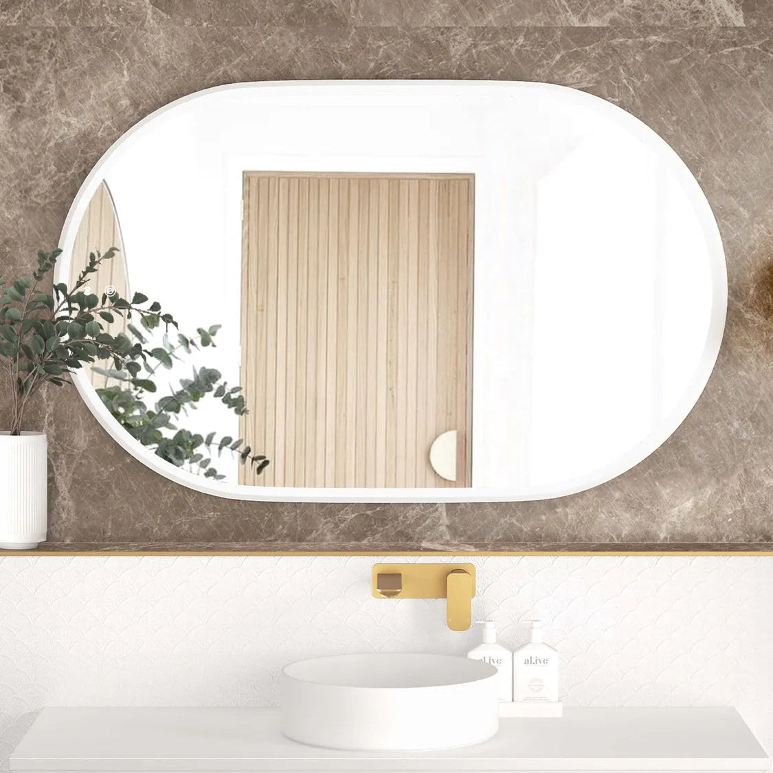 LED Noosa 1200x750 mirror with a white metal frame, featured against a luxurious marble-textured wall. The setup includes a round basin, gold faucet, and a mix of textured materials, blending modern and classic design elements.