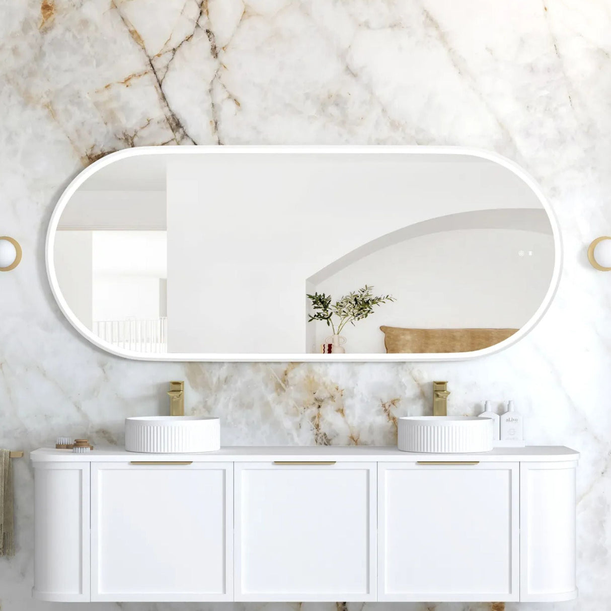 Bathroom vanity with two sinks and a large mirror against a marble wall.