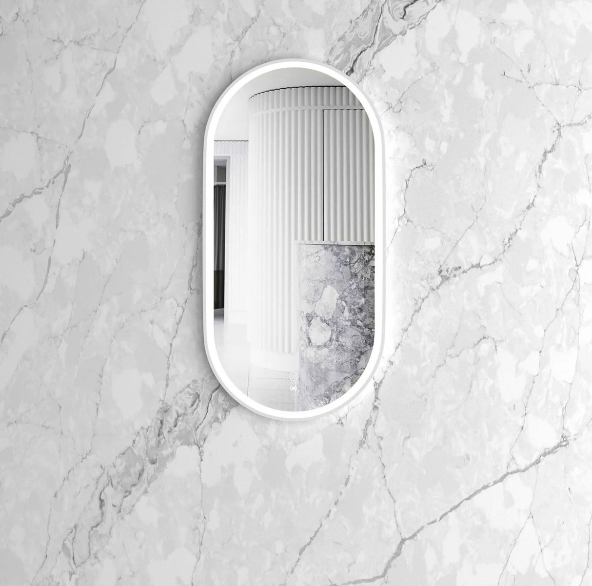 oval mirror with white frame on a marble wall