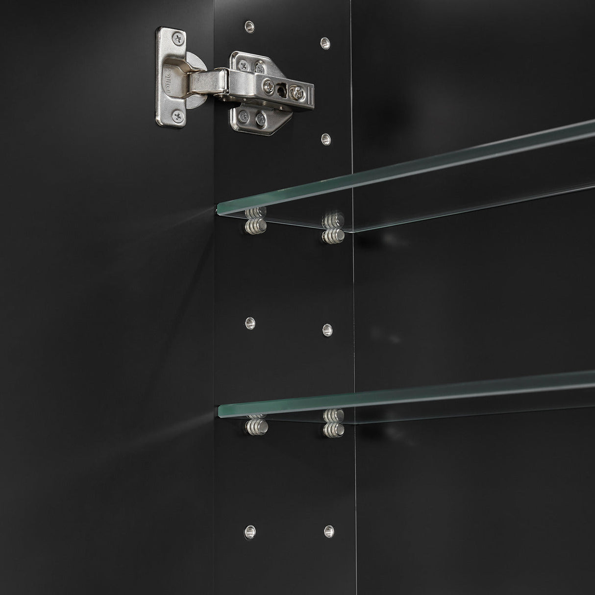 Close-up of a glass shelf with metal brackets on a black background