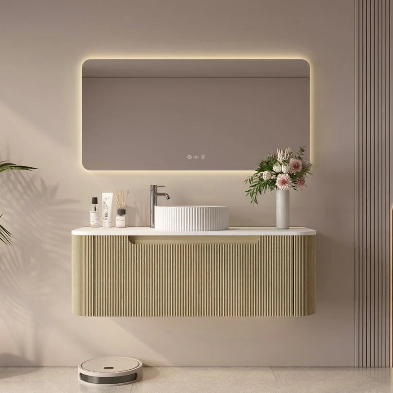 Modern bathroom vanity with illuminated mirror, sink, and decorative elements.