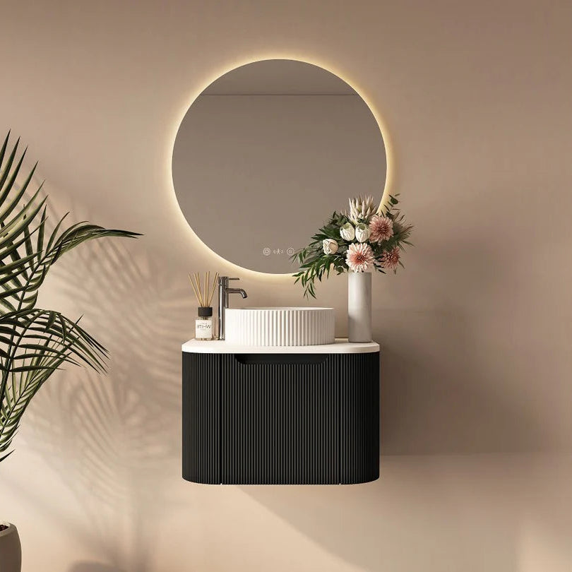 Modern bathroom setup with round mirror, black vanity, and decorative elements.