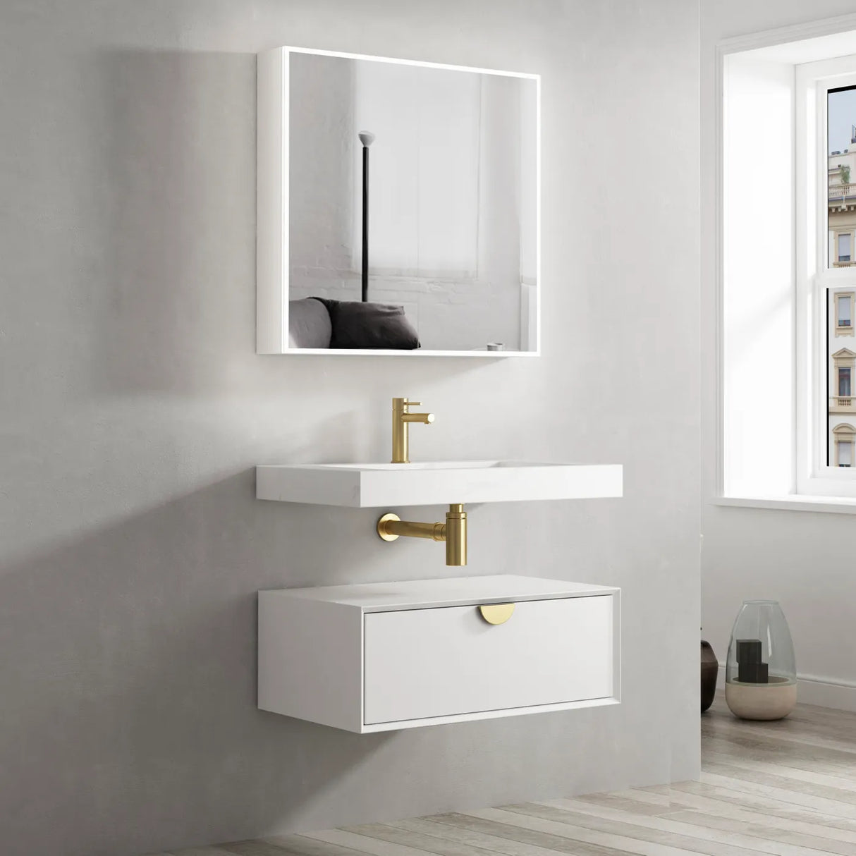 Bathroom vanity with white sink and mirror, gold fixtures, and a window in the background.