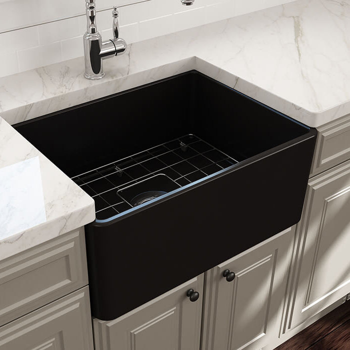 Black farmhouse kitchen sink in a modern kitchen setting with white marble countertop and cabinets.