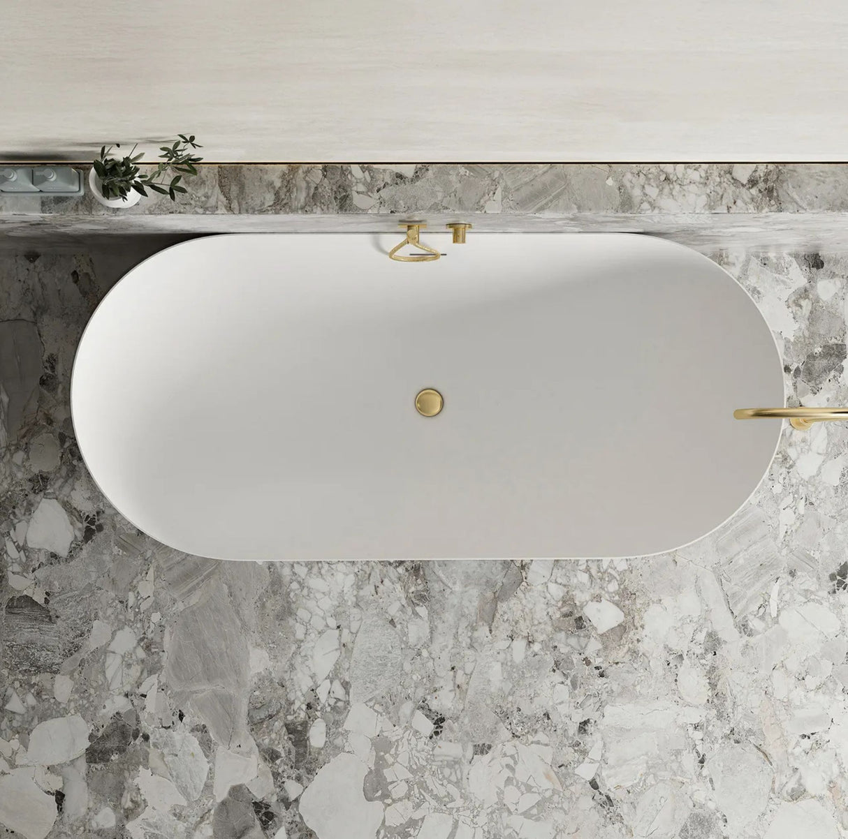 White oval sink with gold fixtures on a marble countertop