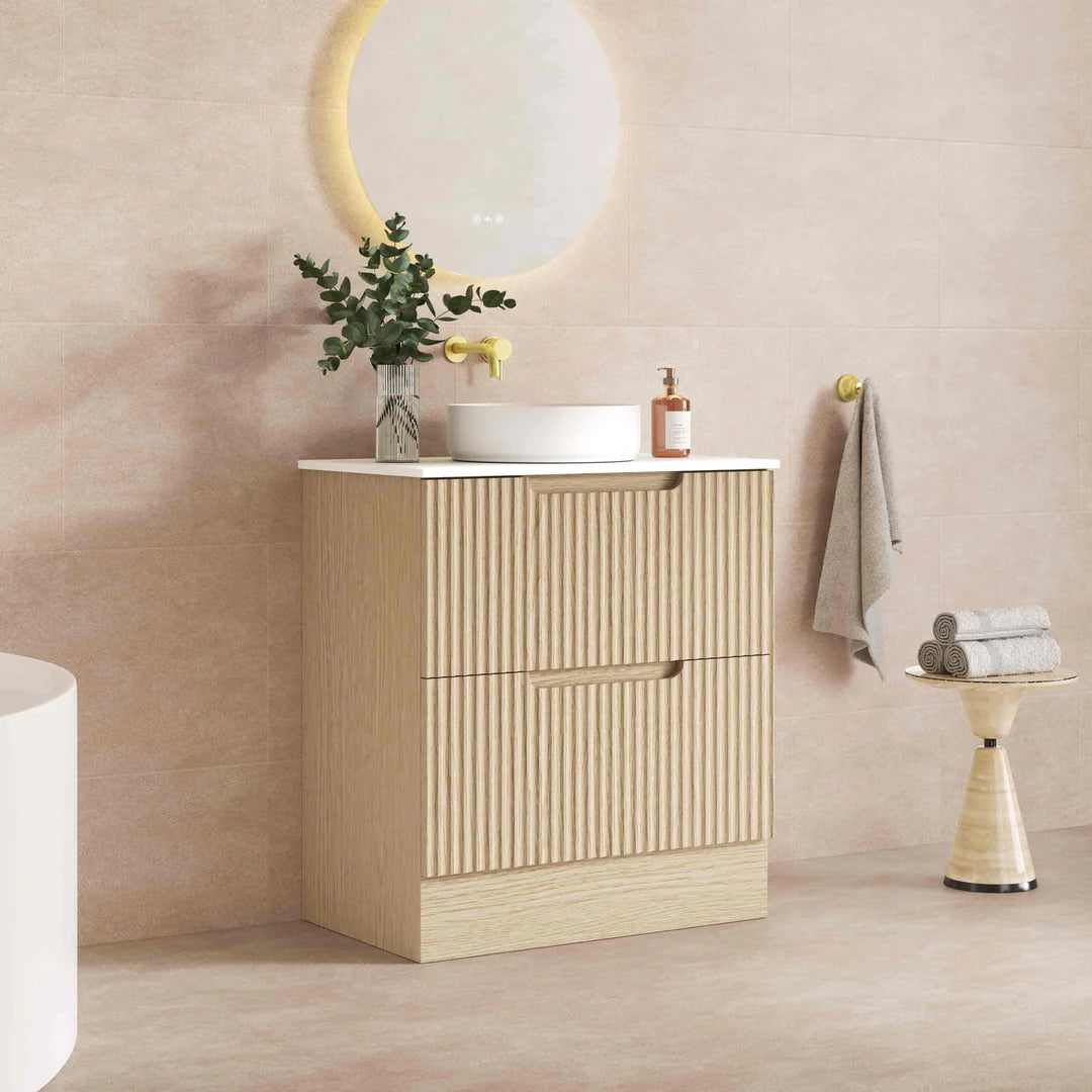 Bathroom vanity with mirror and light fixture against a marble wall.