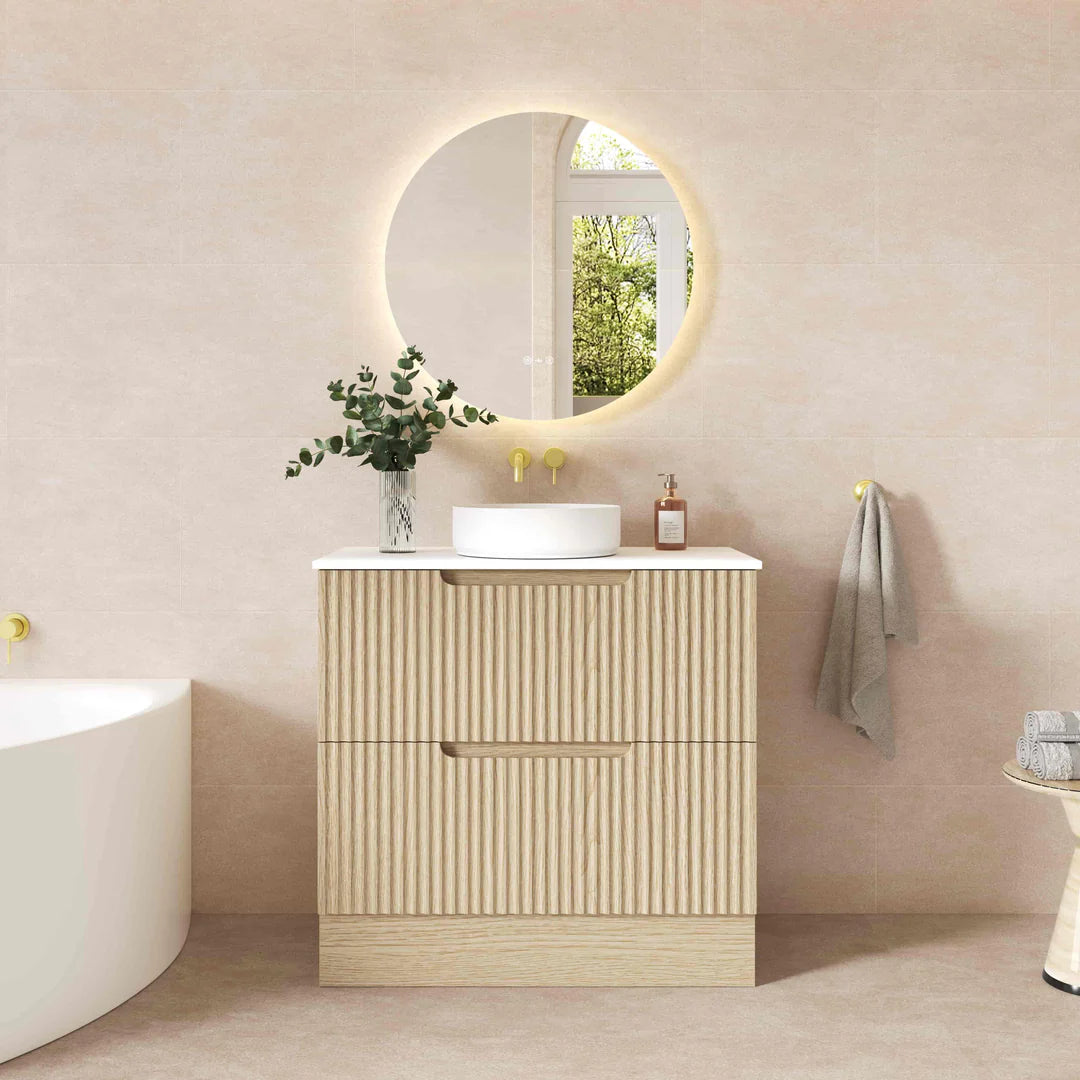 Bathroom vanity with round mirror, sink, and decorative elements against a beige wall.