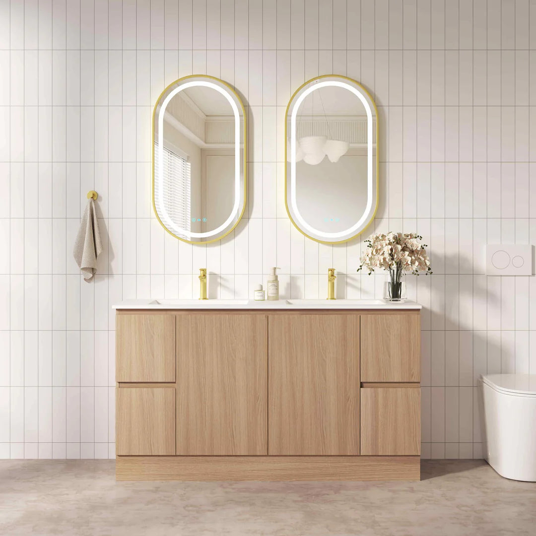 Bathroom vanity with wooden cabinets, white countertop, and two oval mirrors with gold frames.