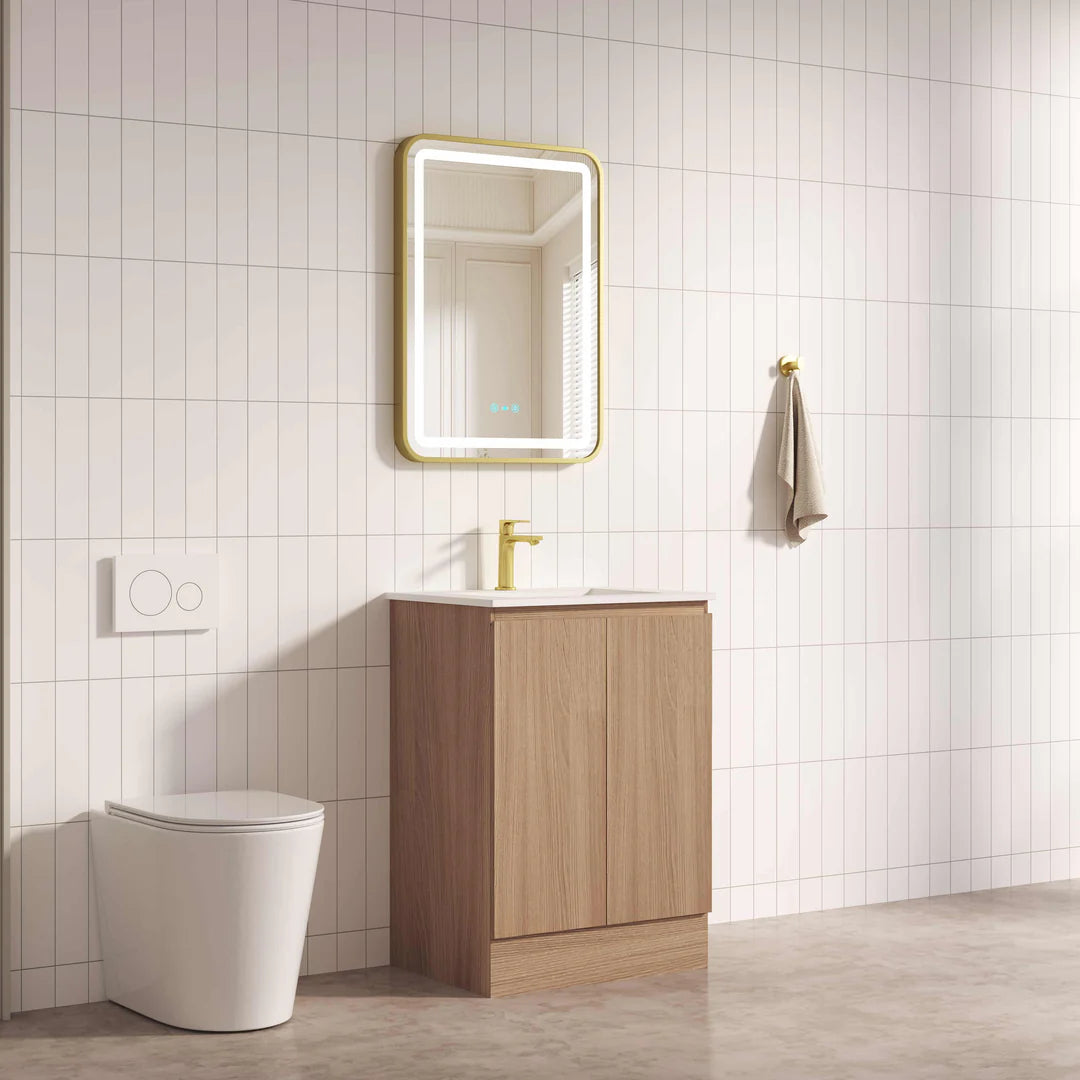 Bathroom with wooden vanity, mirror, and toilet against a tiled wall.