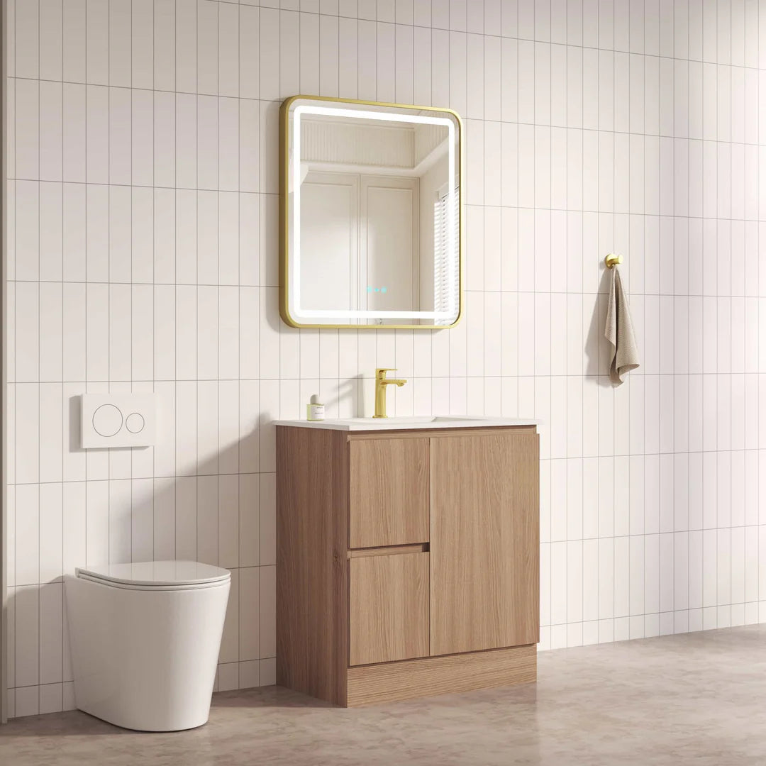 Bathroom setup with wooden vanity, mirror, and toilet against a tiled wall.