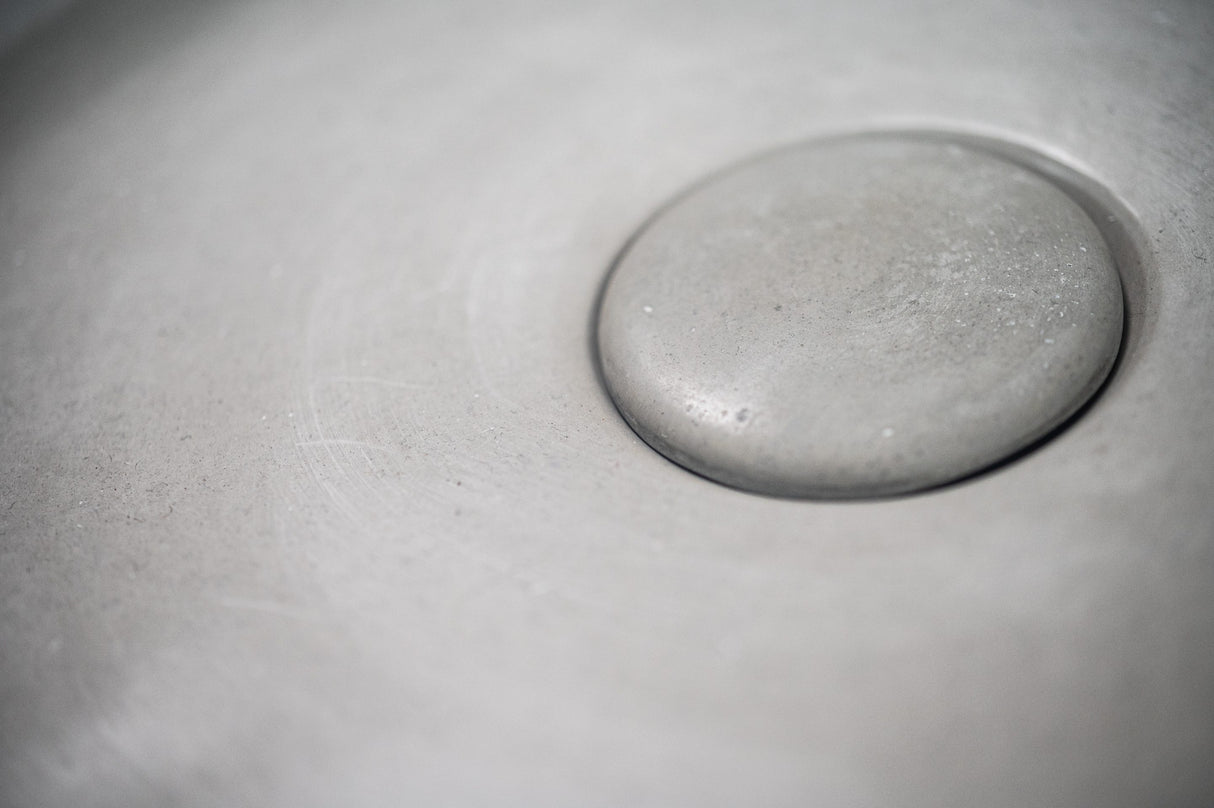 Close-up of the ARLO Round Concrete Basin in Cement Color, showcasing the fine texture and smooth finish of its integrated circular drain, ideal for modern minimalist bathroom designs.