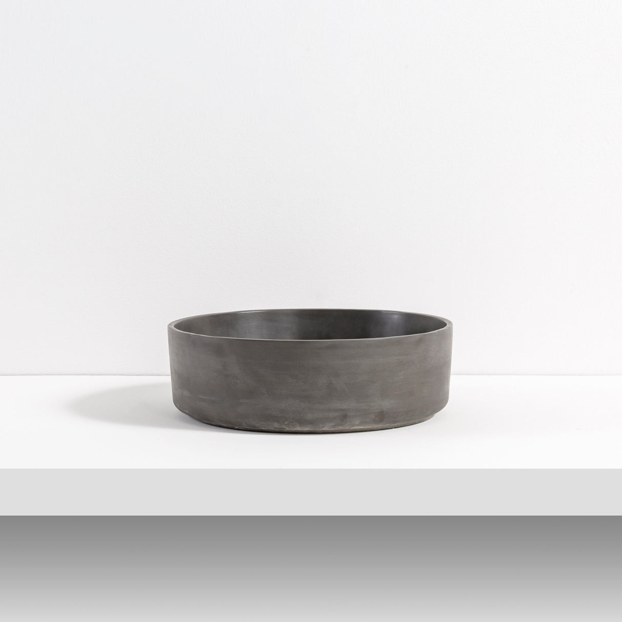 ARLO Round Concrete Basin in Charcoal, showcasing its sleek, low-profile design with a smooth matte finish, ideal for contemporary bathroom settings.