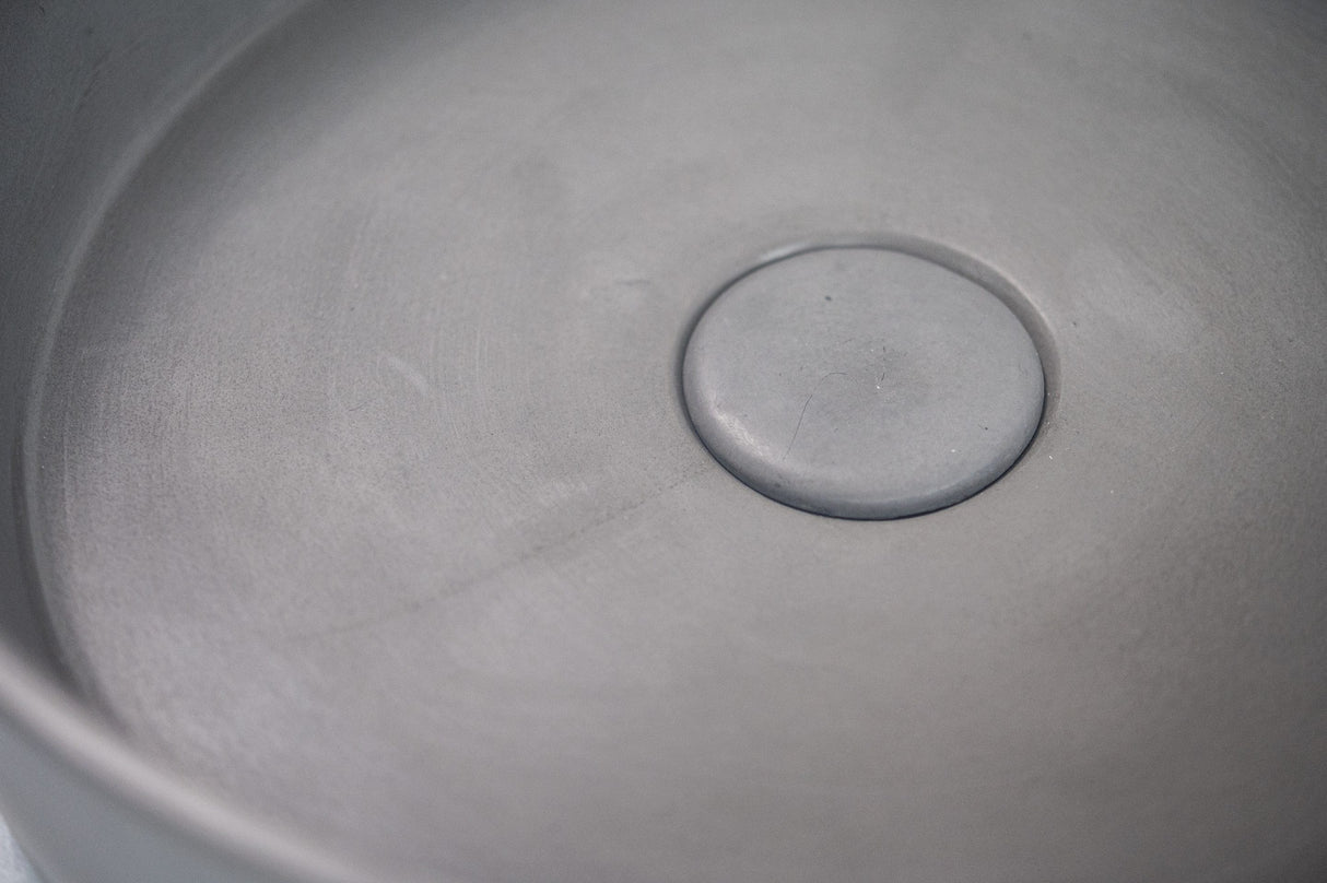 Detailed view of the ARLO Round Concrete Basin in Grey, highlighting its smooth concrete surface and integrated drain design.