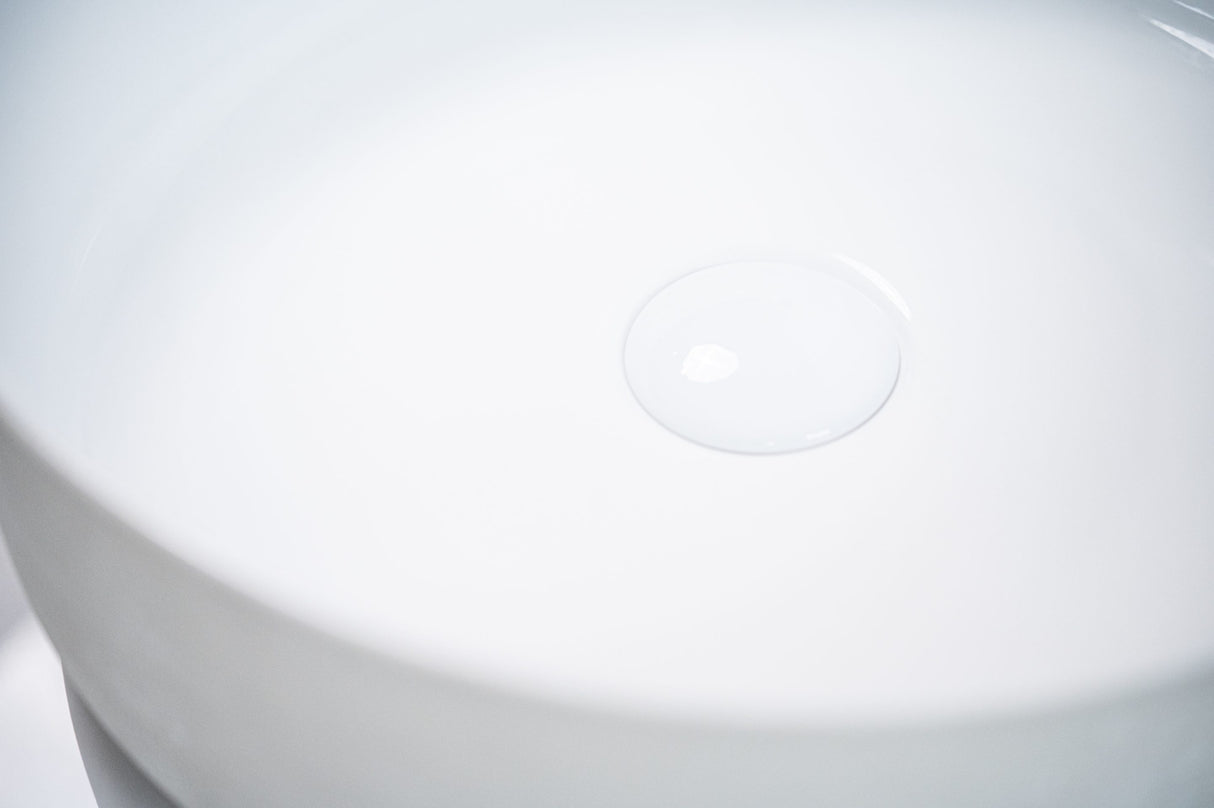 Close-up view of a sleek white ceramic basin, highlighting its smooth curved edges and central drain design, emphasizing a minimalist and modern aesthetic.