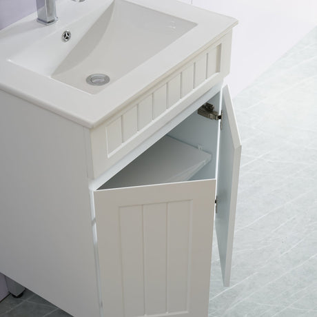 White bathroom vanity with sink and open cabinet door on a tiled floor.