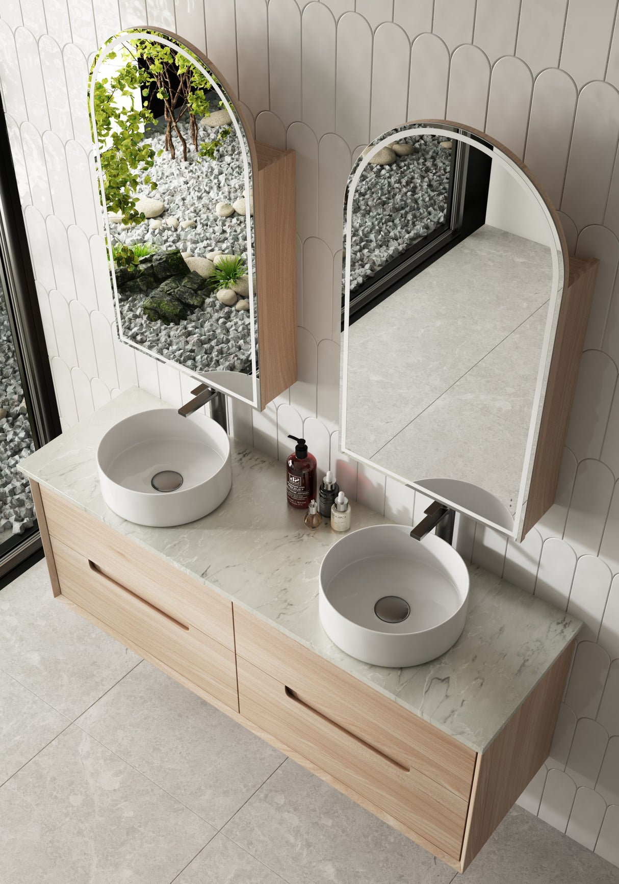 Bathroom vanity with two round sinks, mirrors, and toiletries on a tiled wall.